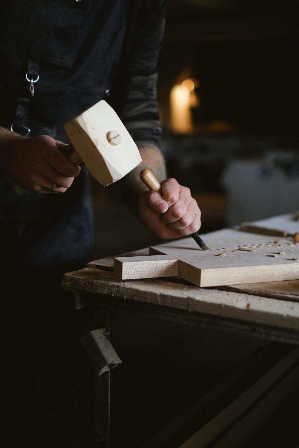 Un artesano utiliza hábilmente un mazo y un cincel para tallar madera en un taller.